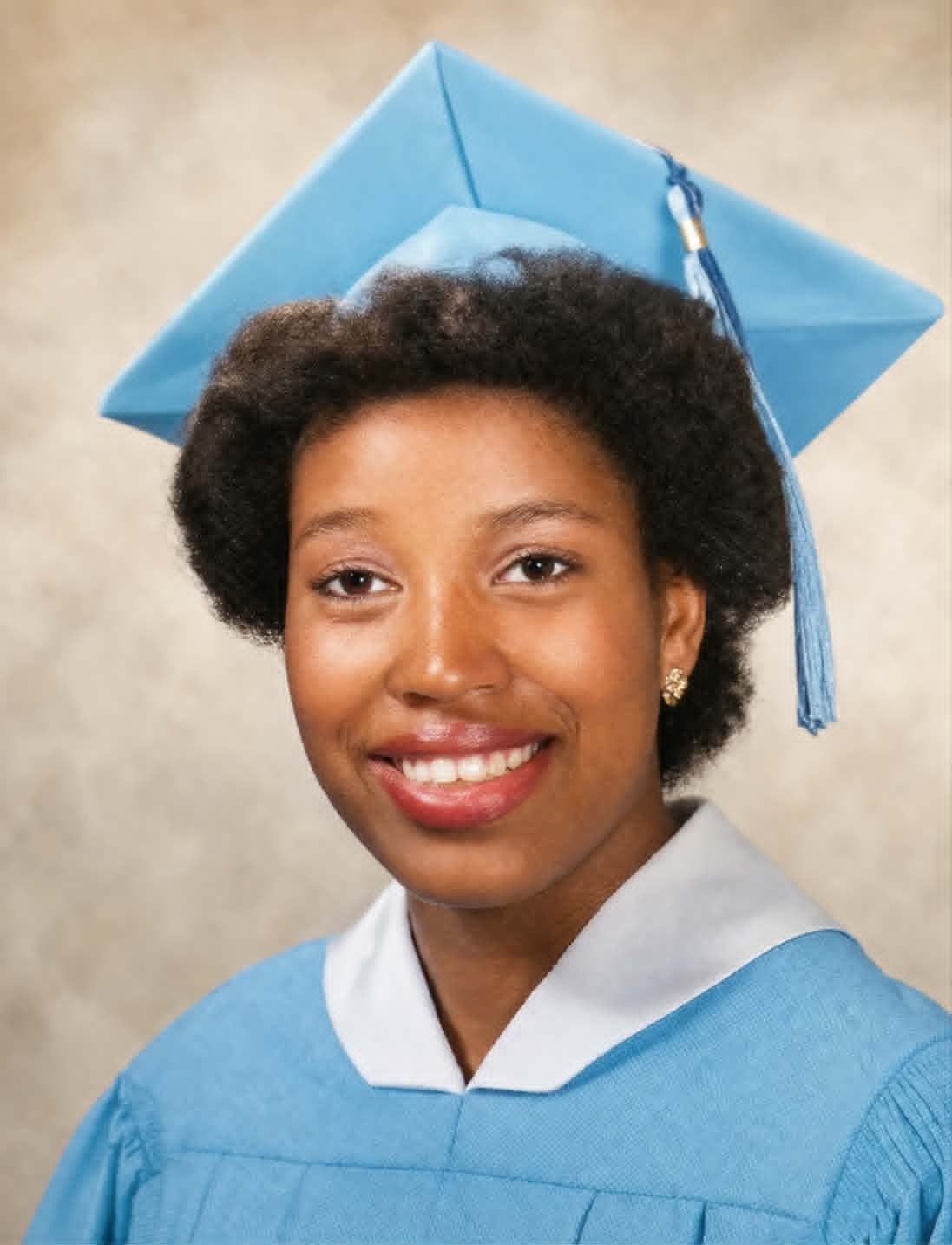 Graduate in light blue cap and gown, smiling portrait