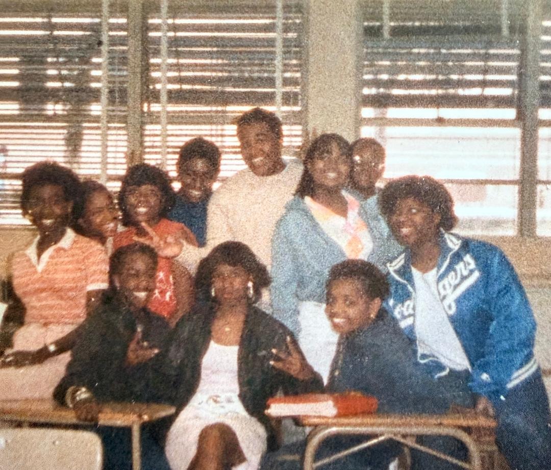 Group of students gathered together in a classroom, smiling and laughing