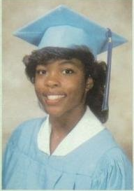 Graduate in light blue cap and gown smiling portrait