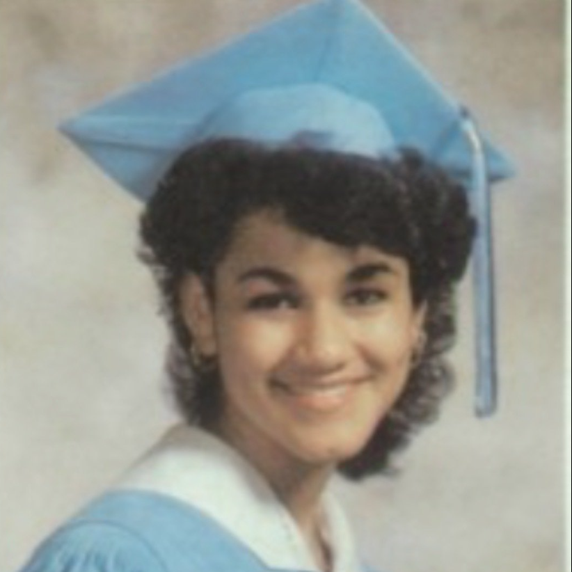 Graduate in light blue cap and gown smiling portrait