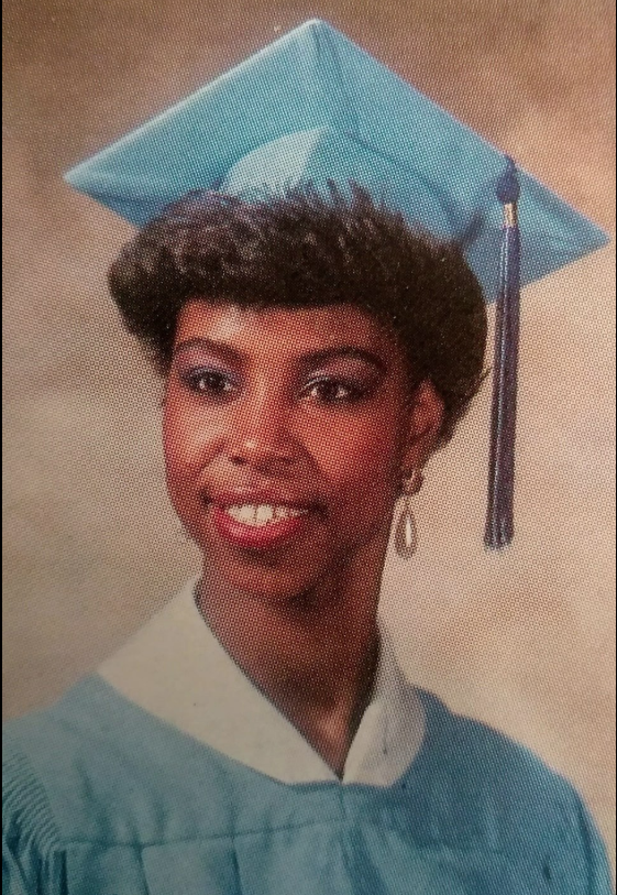 Graduate in teal cap and gown smiling portrait