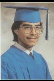 Graduate in blue cap and gown with glasses portrait