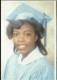 Graduate in light blue cap and gown smiling portrait