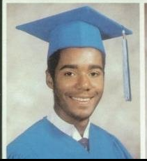 Young man in light blue cap and gown graduation portrait