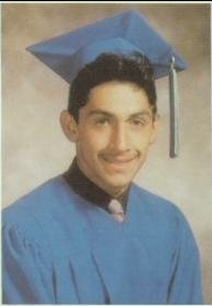 Young man in light blue cap and gown graduation portrait