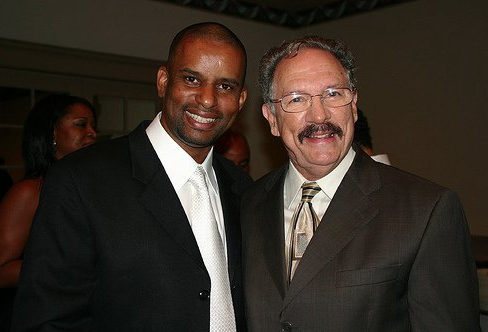 Two men in formal suits smiling together at an event