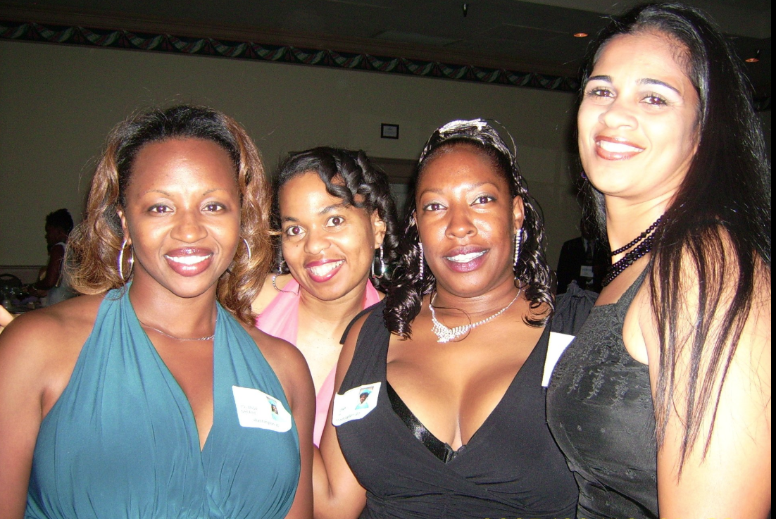 Four women smiling together at a reunion event