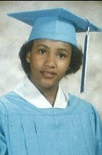 Young woman in light blue cap and gown graduation portrait