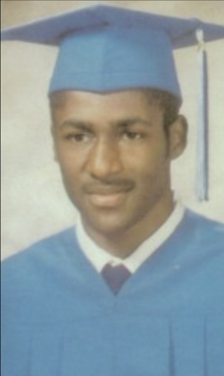 Young man in light blue cap and gown graduation portrait