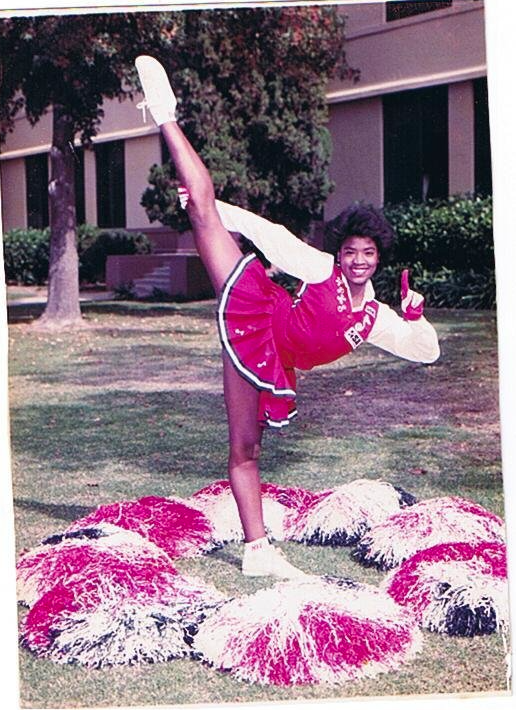 Washington Generals cheerleader in red and white uniform performing a high kick with pom poms