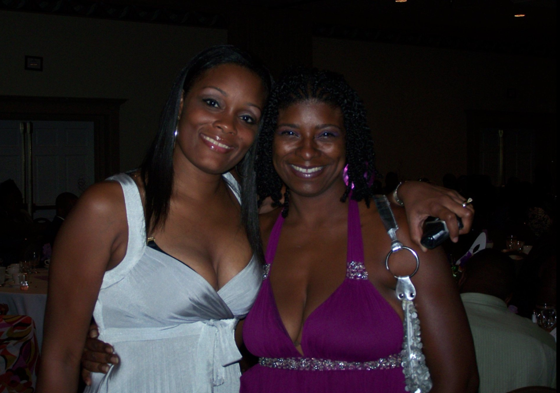 Two women smiling together at a reunion event indoors