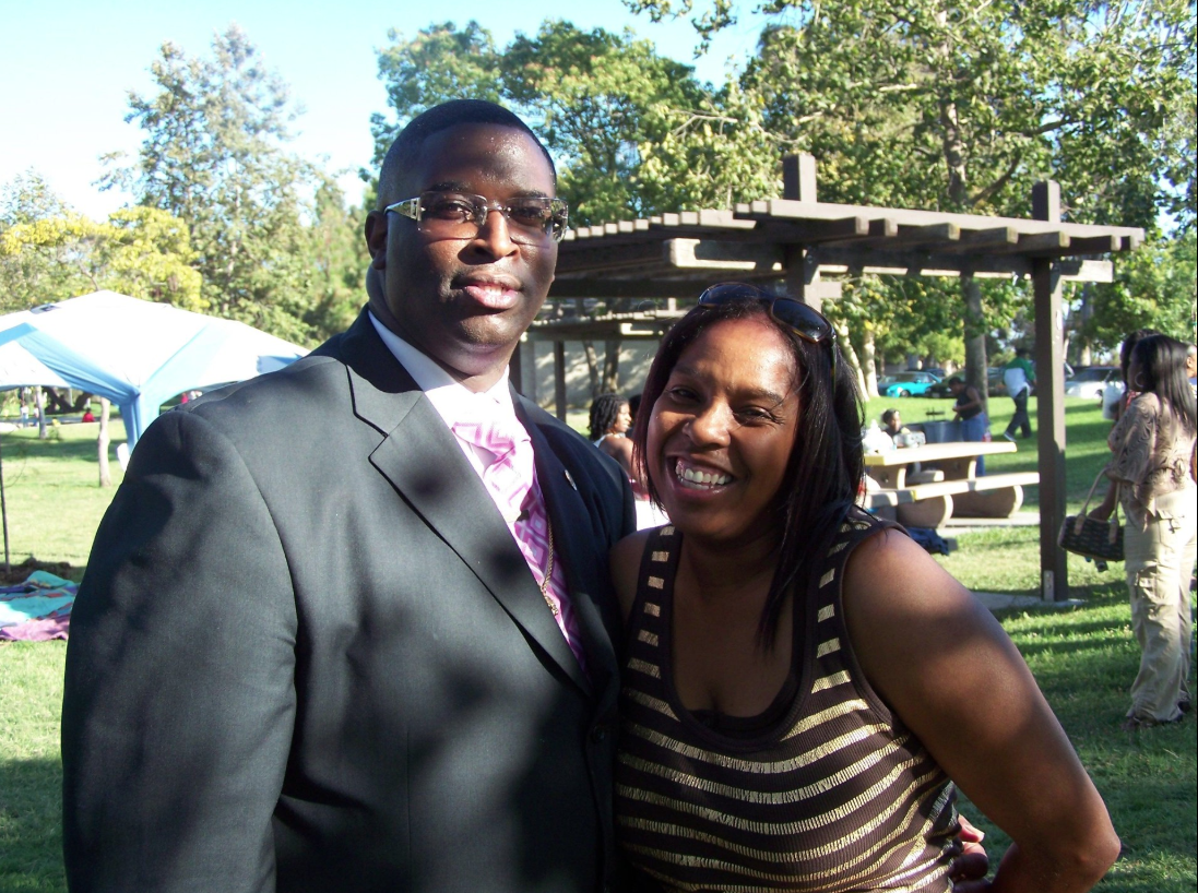 Man in suit and woman in striped top smiling together at an outdoor reunion picnic